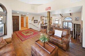 A spacious living room with a fireplace, a dining area, and a view of the outdoors. - Over 5,700 Square Feet of Lakeside Luxury! Private Dock! Hot Tub! Game Room! Arcade Room! Beach! Patio Gazebo! Ornate Iron and Marble Accents! (Big Bear Lake)