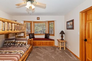 A room with a bed, a window seat, a lamp, and a door. - Over 5,700 Square Feet of Lakeside Luxury! Private Dock! Hot Tub! Game Room! Arcade Room! Beach! Patio Gazebo! Ornate Iron and Marble Accents! (Big Bear Lake)