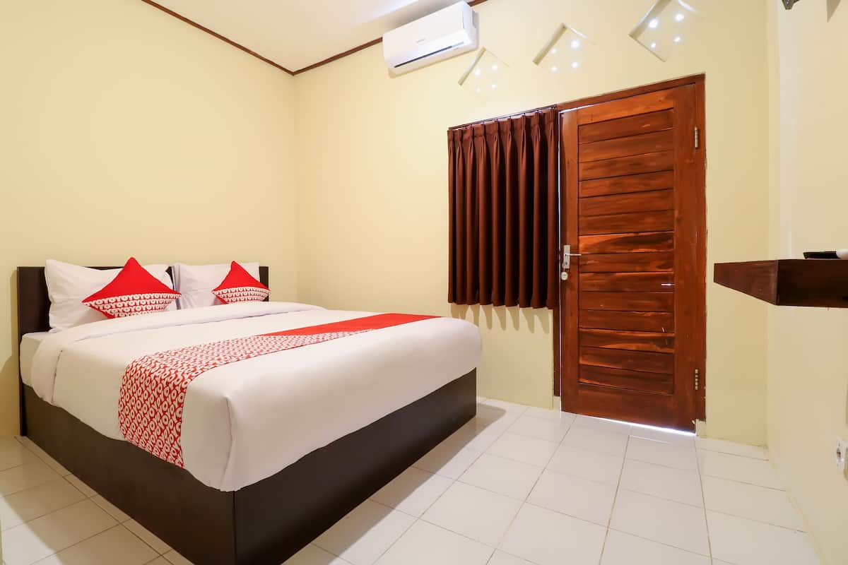 A neatly made bed with a white and red bedspread, a wooden headboard, and red and white pillows.