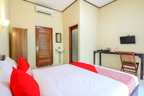 A hotel room with a bed, a desk, a chair, a TV, and a door. - Hotel O Kenanga Homestay (Nusa Dua)