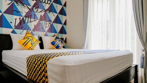 Una cama bien tendida con un colchón blanco y una colcha estampada.