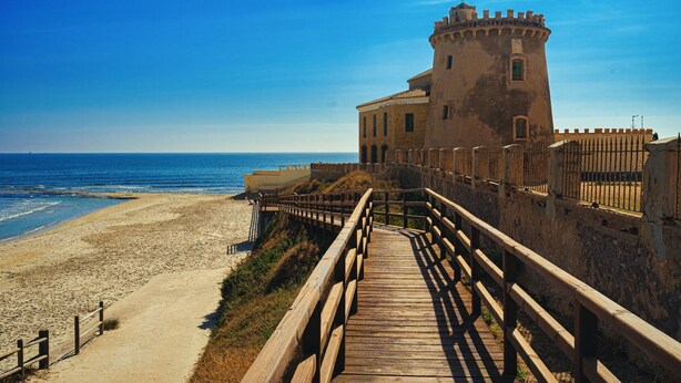 A coastal building with a wooden walkway leading to the beach. - Apartamento Vela (Torre de la Horadada) (Pilar de la Horadada)