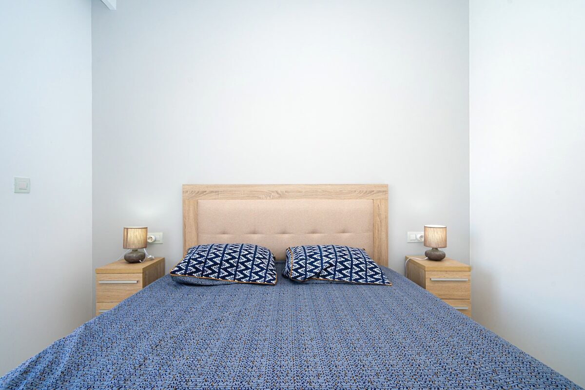 Ein Schlafzimmer mit einem Bett, zwei Kissen, zwei Nachttischen und zwei Lampen.