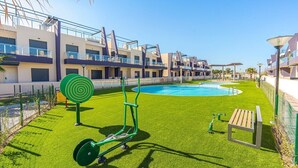 A modern hotel with a swimming pool, exercise equipment, and a well-maintained lawn. - Apartamento Vela (Torre de la Horadada) (Pilar de la Horadada)