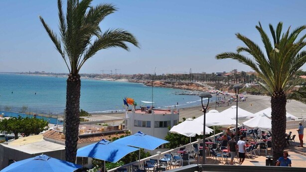 A coastal view with palm trees, a beach, and a restaurant area with umbrellas and outdoor seating. - Villa Stachera (San Pedro del Pinatar) (San Pedro del Pinatar)