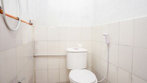 A small, white-tiled bathroom with a toilet, a white toilet paper holder, and a white handheld showerhead. - OYO 2369 Cempaka Homestay (Rancabali)