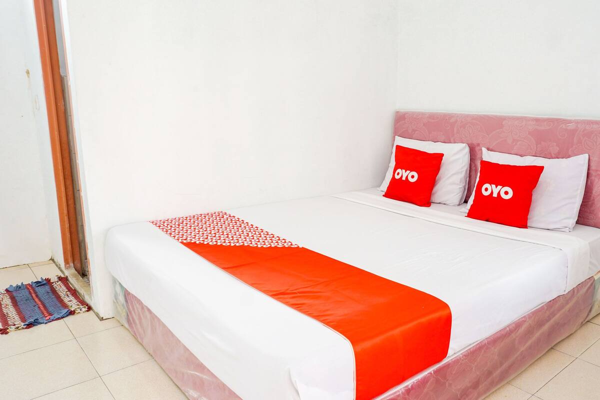 A bed with a red and white bedspread, two red pillows with "OYO" text, and a red blanket.