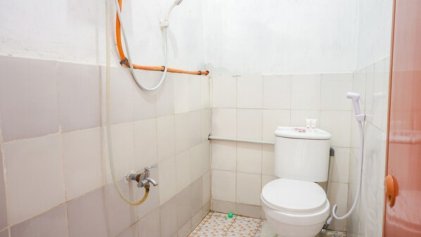 A small, white-tiled bathroom with a toilet, a shower, and a hand dryer.