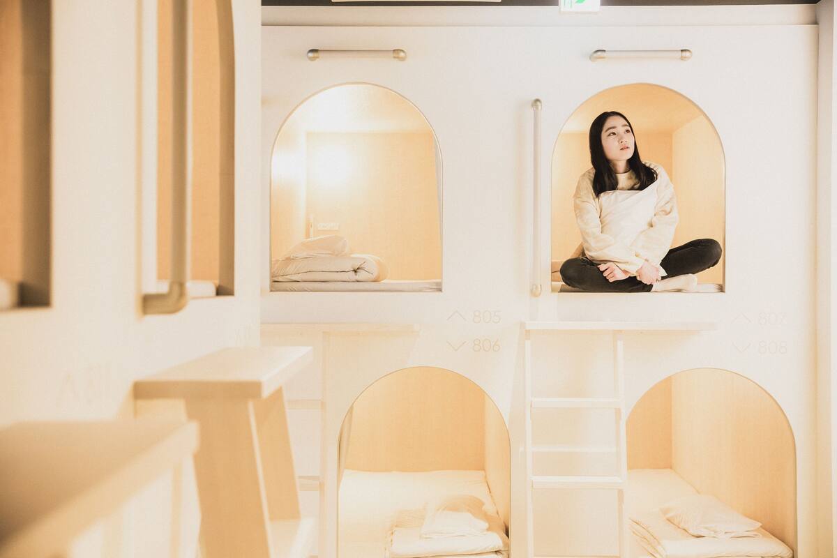 Une chambre d’hôtel avec des lits superposés, une échelle et une petite fenêtre.