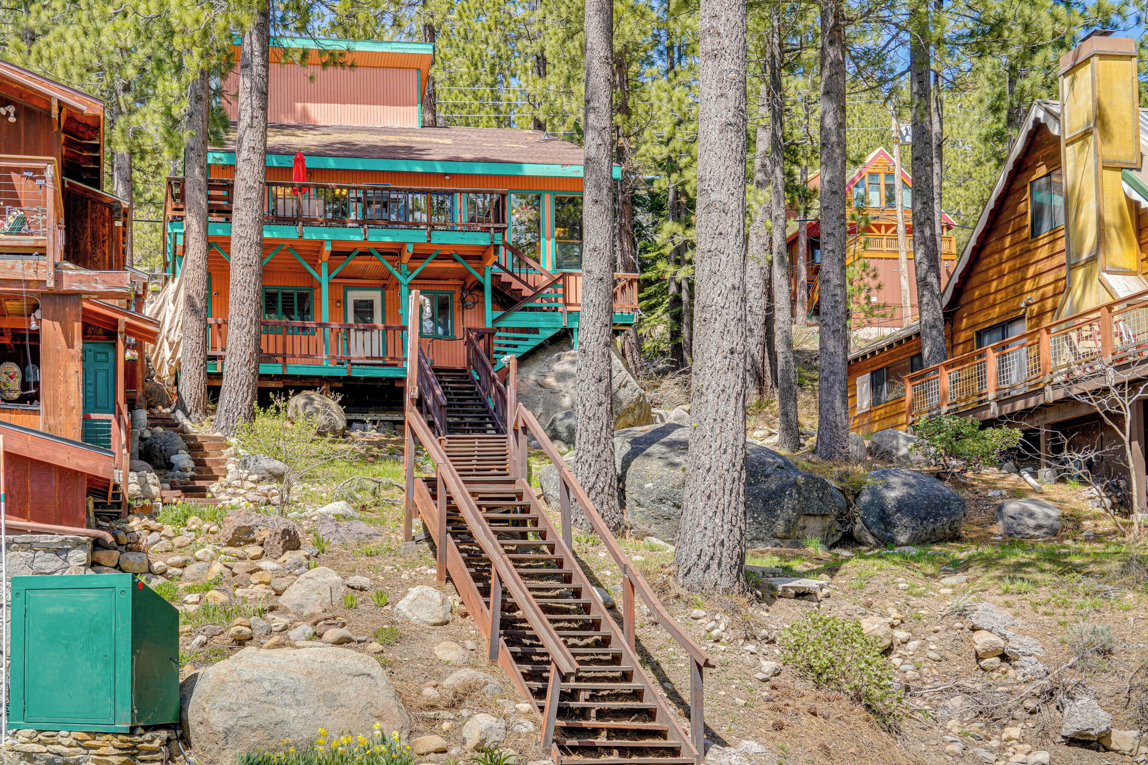 A rustic cabin with a wooden exterior, a staircase leading to a porch, and a surrounding forest.