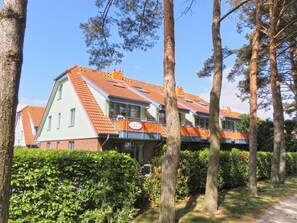 Un bâtiment moderne doté d’un toit en pente, de grandes fenêtres et d’un balcon avec des garde-corps orange.
