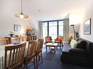 Un salon confortable avec un canapé, des fauteuils, une table à manger et une grande fenêtre.