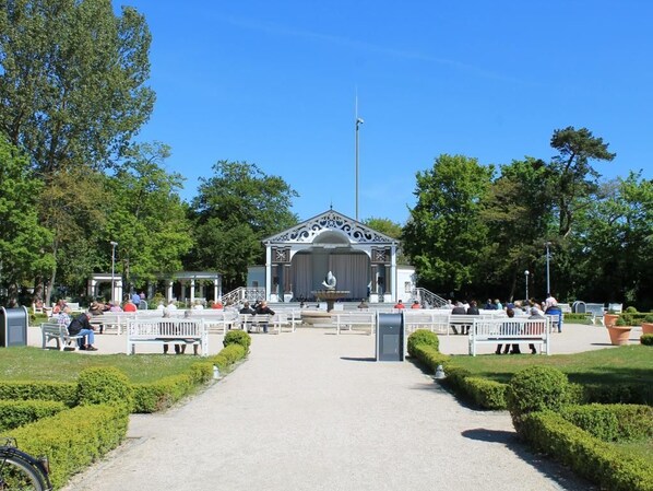 Een gazebo met een podium, omringd door banken en paden in een park.