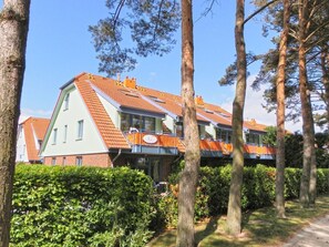 Un bâtiment moderne doté d’un toit en pente, de grandes fenêtres et d’un balcon avec des garde-corps orange.