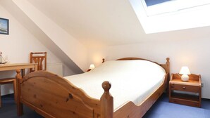 Quarto com cama de madeira, escrivaninha e cadeira.