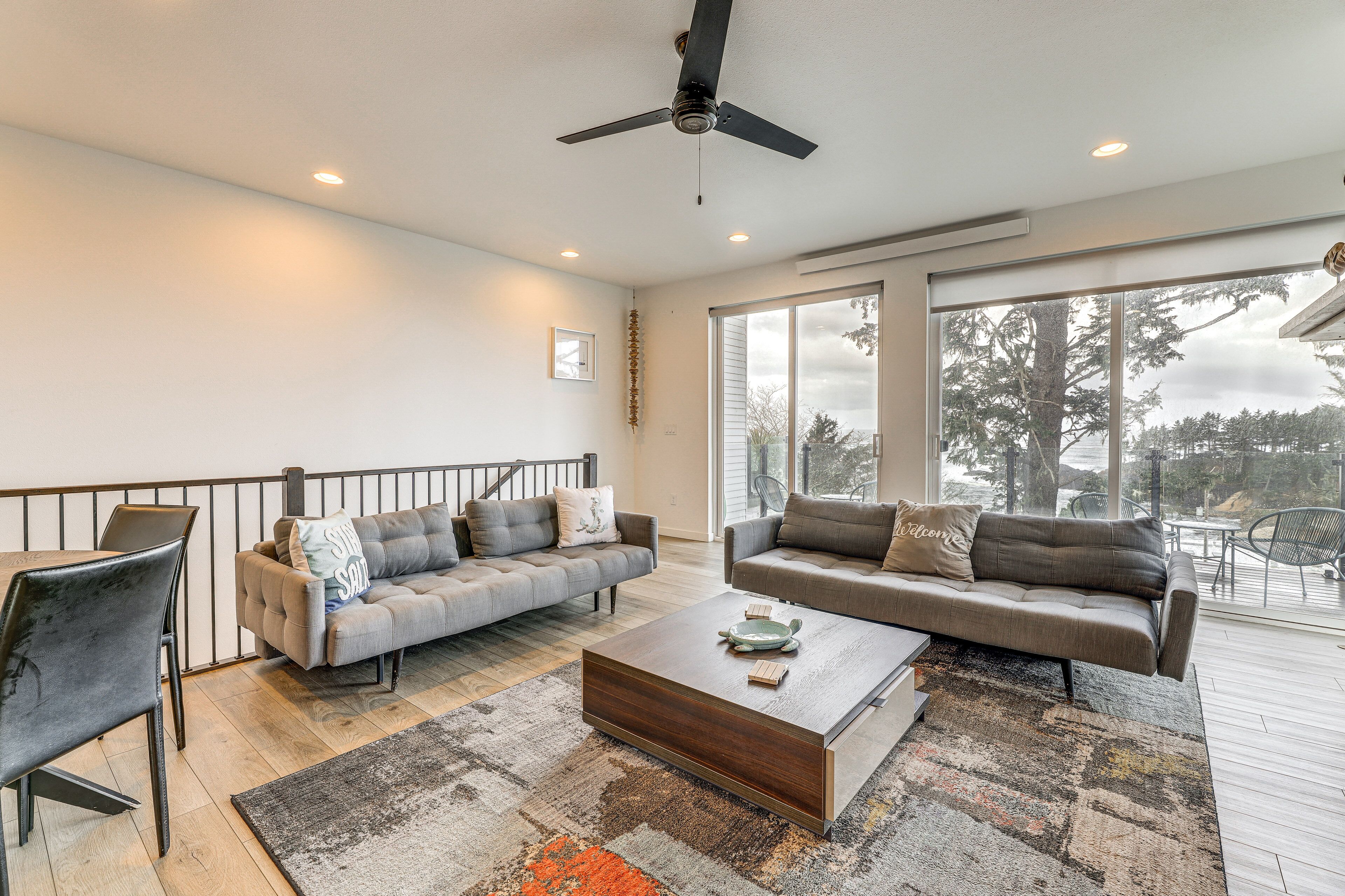 A spacious living room with two grey sofas, a wooden coffee table, and a ceiling fan.