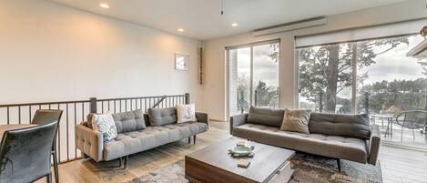 A spacious living room with two grey sofas, a wooden coffee table, and a ceiling fan.