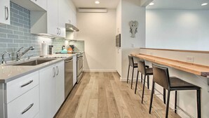 Une cuisine moderne avec des armoires blanches, un plan de travail en bois et un four encastré.