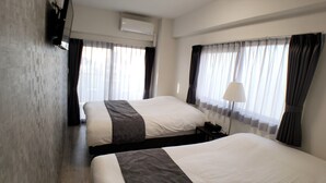 A hotel room with two beds, a bedside table with a lamp, and a window with curtains. - Ocean View Araha 305 (Chatan)