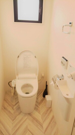 Ein kleines, kompaktes Badezimmer mit Toilette, Bidet und einem Fenster über der Toilette.