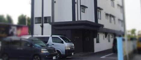 Un edificio moderno con fachada blanca y detalles negros, que cuenta con varios pisos y un techo plano.