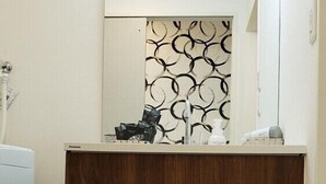 A bathroom with a wooden vanity, a mirror, and two towel racks. - Ocean View Araha 301 (Chatan)