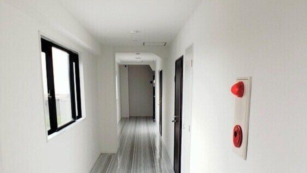 A narrow hallway with a striped floor, white walls, and a door at the end. - Ocean View Araha 301 (Chatan)