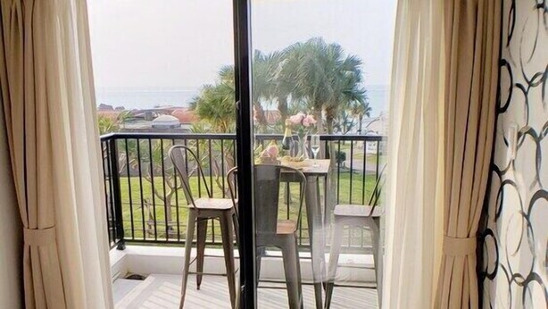 A hotel room with a bed, a balcony with a table and chairs, and a view of the outdoors. - Ocean View Araha 205 (Chatan)