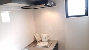 A compact kitchen with a sink, a small countertop, a window, and a trash bin. - Ocean View Araha 205 (Chatan)
