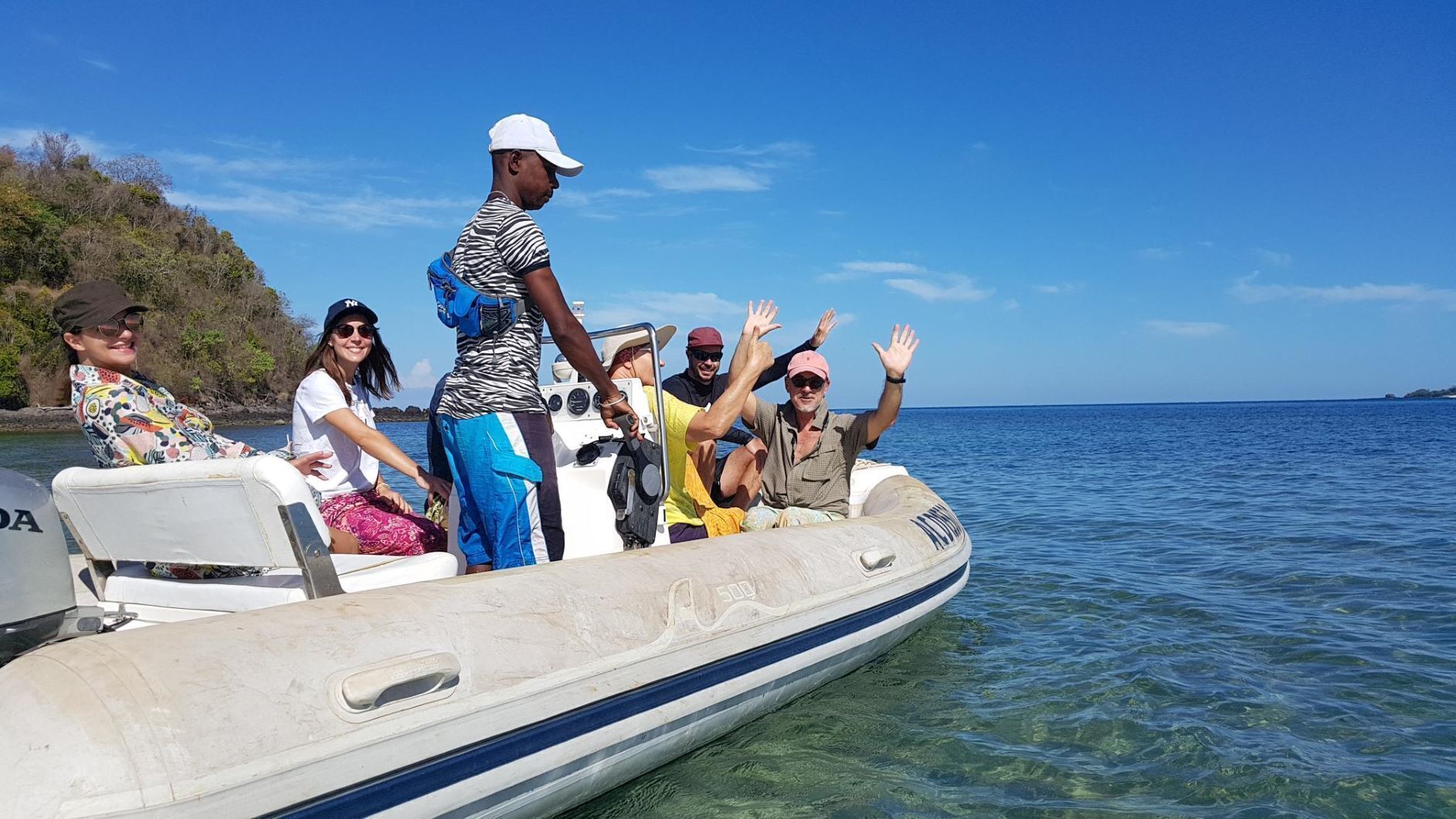 A group of people on a small boat with a clear view of the water and a distant shoreline.