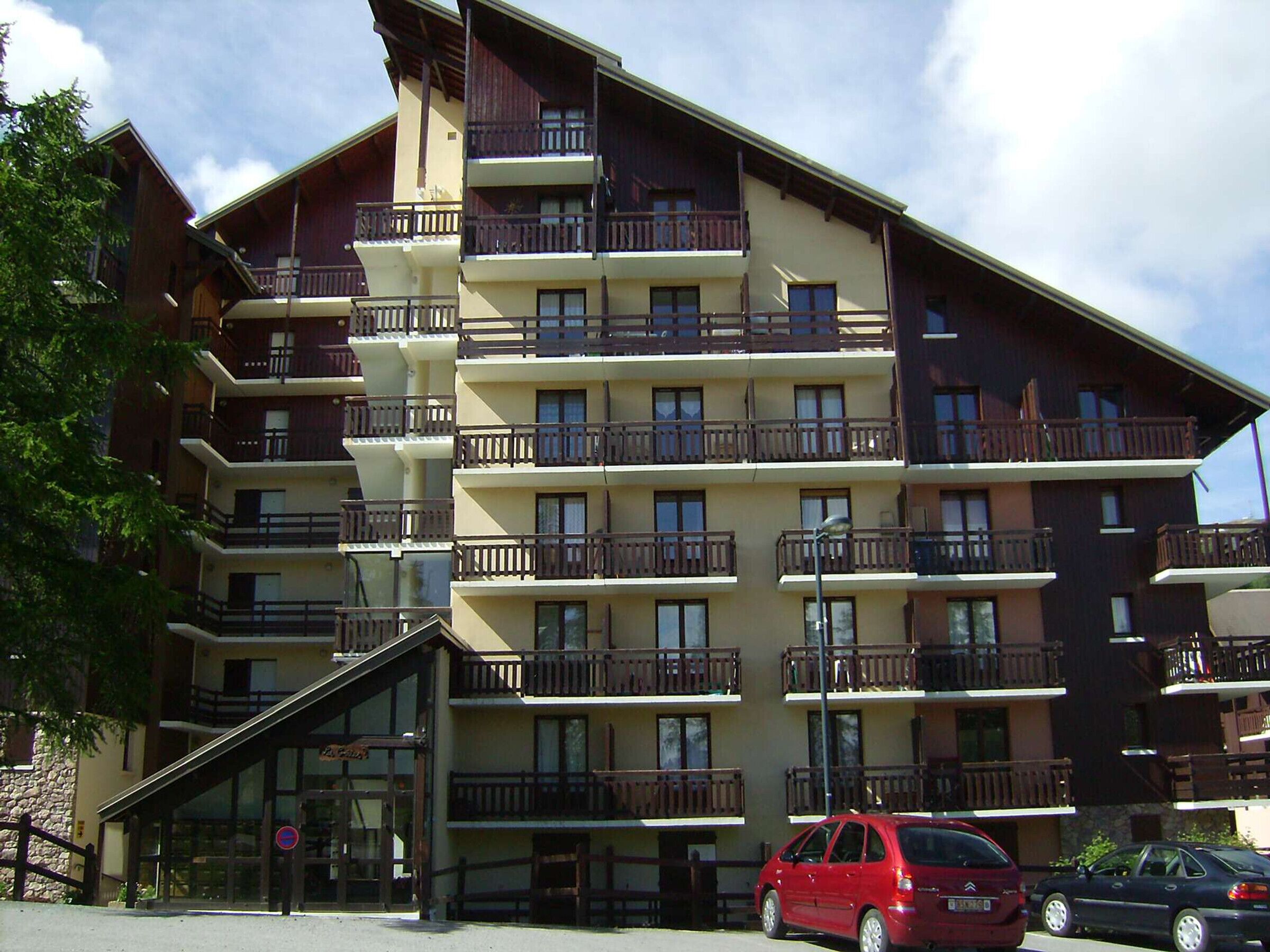 Un hotel a più piani con balconi, ingresso in vetro e facciata in pietra.