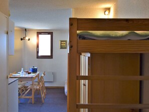 A room with a bunk bed, a table with chairs, a window, and a wall-mounted light fixture. - Tranquil Studio Cabin for 4 with Ski Locker – Pet Friendly, Free Parking, Near Shuttle (Risoul)