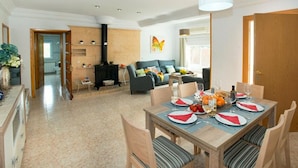 A dining area with a table set for four, a sofa, and a kitchen in the background. - Villa Montelo with private pool near the sea (Alcúdia)