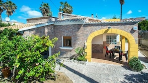 A stone building with a yellow archway leading to an outdoor seating area. - Villa Montelo with private pool near the sea (Alcúdia)