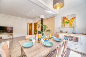 Uma sala de jantar moderna com mesa de madeira, cadeiras e diversos pratos e bebidas.