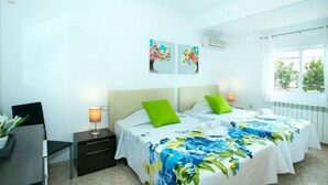 A hotel room with two beds, a desk, and a chair. There are two wall-mounted air conditioning units. - Villa Montelo with private pool near the sea (Alcúdia)