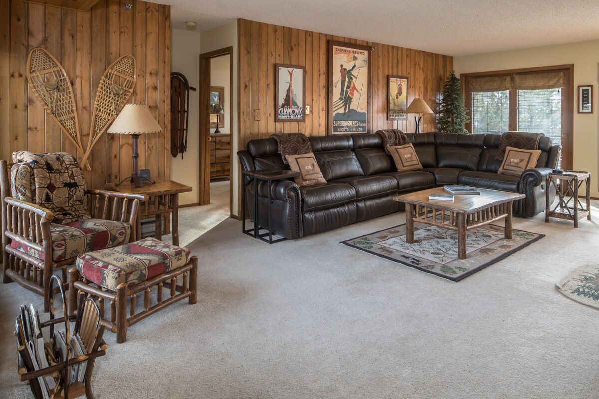 A cozy living room with a leather sofa, wooden chairs, and a small table.