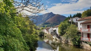 A riverside village with traditional houses, a bridge, and a mountain in the background. - T4 + terrace - Meublé de tourisme 3*** - Basque Coast / Sea and mountains (Saint-Pée-Sur-Nivelle)