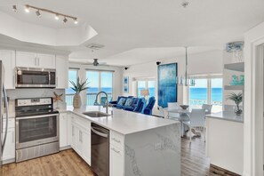 A modern kitchen with a large island, built-in appliances, and a view of the ocean.
