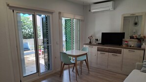 A room with a dining table, chairs, a TV, and a kitchen area. - Apartment in El Alamillo (Puerto de Mazarrón)