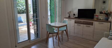 Une pièce comprenant une table à manger, des chaises, un téléviseur et un coin cuisine.