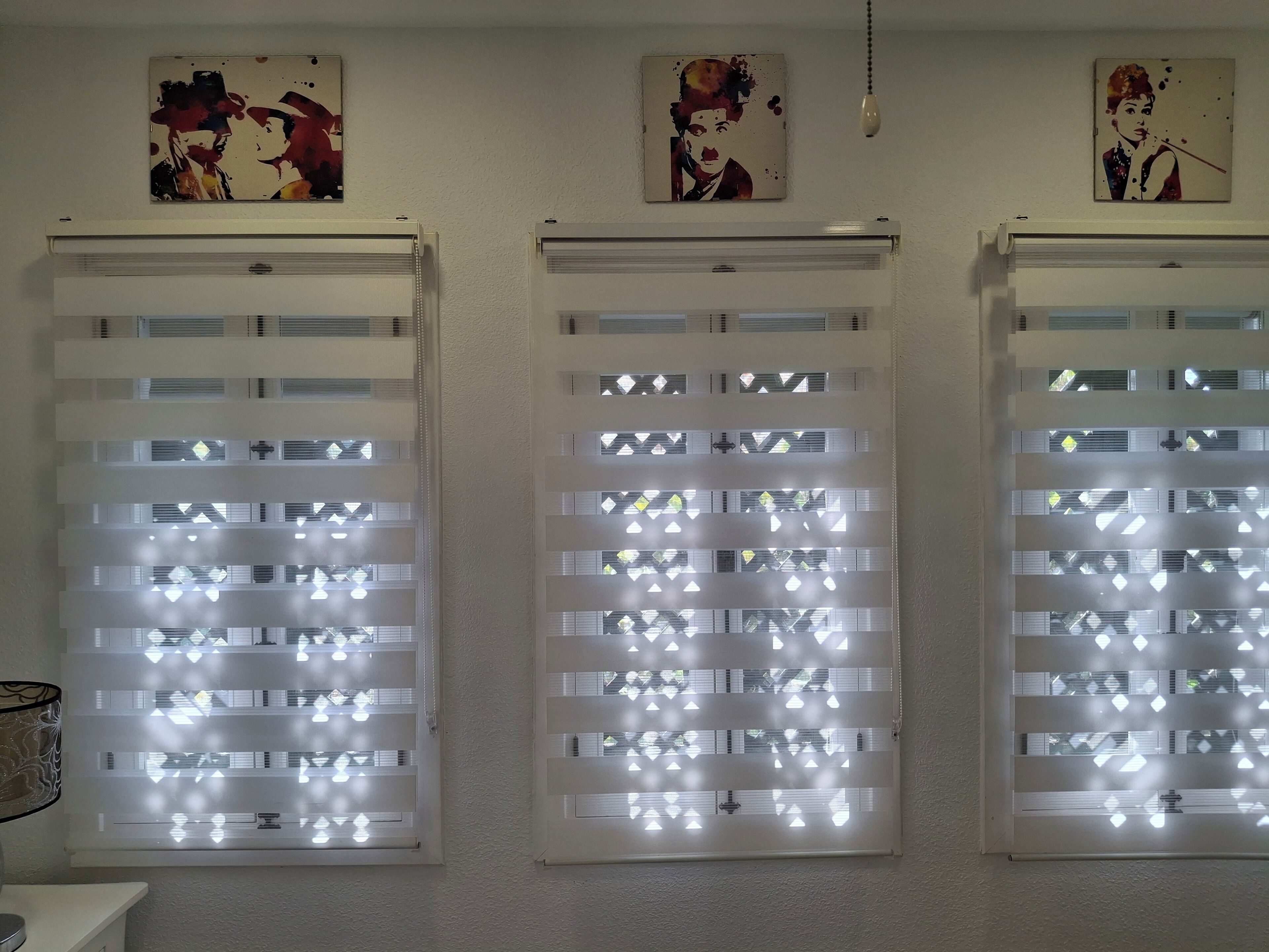 Trois fenêtres dotées de vitres dépolies et ornées de motifs décoratifs, chacune étant surmontée d’un luminaire encastré au plafond.