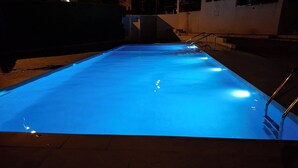 A rectangular swimming pool with a blue light, metal handrails, and a tiled floor. - Apartment in El Alamillo (Puerto de Mazarrón)