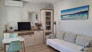 A modern living room with a sofa, a dining table with chairs, a TV, a cabinet, and a painting on the wall. - Apartment in El Alamillo (Puerto de Mazarrón)