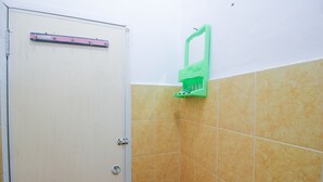 A bathroom with yellow tiles, a white door, and a green towel rack. - SPOT ON 2370 Berkah Homestay Syariah (Pekanbaru)