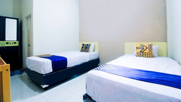 A hotel room with two beds, a wooden desk, and a wardrobe. - SPOT ON 2370 Berkah Homestay Syariah (Pekanbaru)