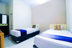 Habitación de hotel con dos camas, un escritorio de madera y un armario.
