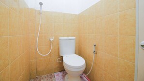 A small bathroom with a toilet, a shower, and tiled walls. - SPOT ON 2370 Berkah Homestay Syariah (Pekanbaru)