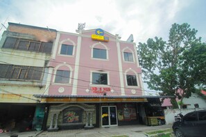 A pink building with a sign that reads "NDES NUR PENGLIMANA" and a blue arrow sign above it. - SPOT ON 2305 Andys Nur Penginapan (Dumai)