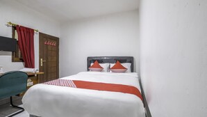 Een hotelkamer met een bed, een bureau, een stoel, een kledingkast en een televisie.